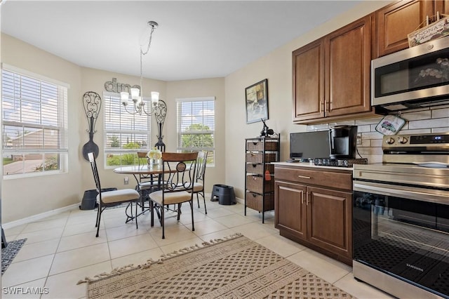 18 SW 19th Ter, Cape Coral, FL 33991 - kitchen featuring stainless steel appliances, a chandelier, baseboards, backsplash, and light tile patterned flooring