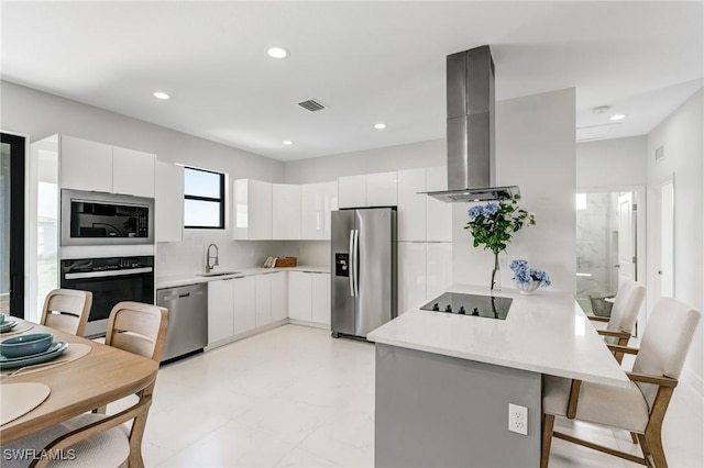 9018 W Castle Cir, Labelle, FL 33935 - kitchen featuring appliances with stainless steel finishes, a peninsula, range hood, a breakfast bar, and white cabinetry