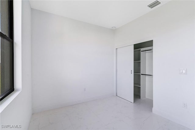 9018 W Castle Cir, Labelle, FL 33935 - unfurnished bedroom with marble look tiles, a closet, and baseboards