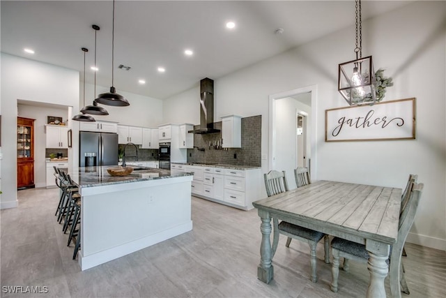 3621 NW 14th St, Cape Coral, FL 33993 - kitchen with wall chimney exhaust hood, stainless steel refrigerator with ice dispenser, dark stone counters, backsplash, and cooktop