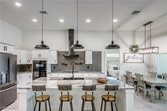 3621 NW 14th St, Cape Coral, FL 33993 - kitchen featuring stainless steel fridge, wall chimney exhaust hood, decorative backsplash, a kitchen bar, and recessed lighting