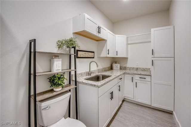 3621 NW 14th St, Cape Coral, FL 33993 - kitchen featuring a sink, light wood-type flooring, white cabinets, and light stone counters
