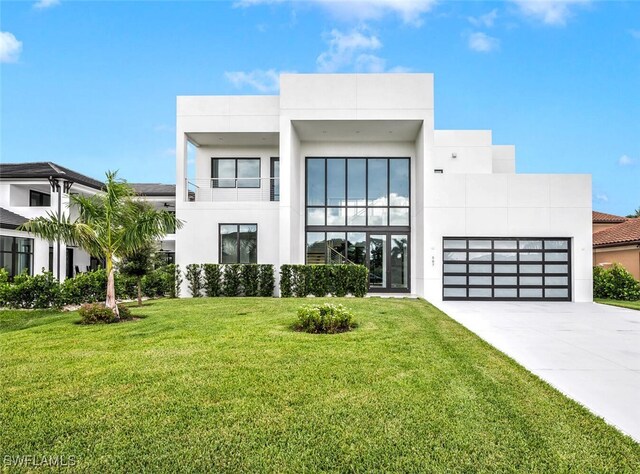 507 107th Ave N, Naples, FL 34108 - contemporary house featuring concrete driveway, a garage, a front lawn, and stucco siding