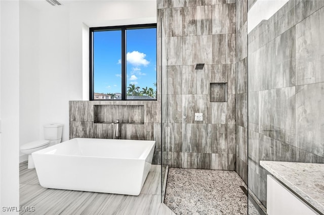 507 107th Ave N, Naples, FL 34108 - full bathroom featuring a freestanding tub, toilet, tile walls, tiled shower, and vanity