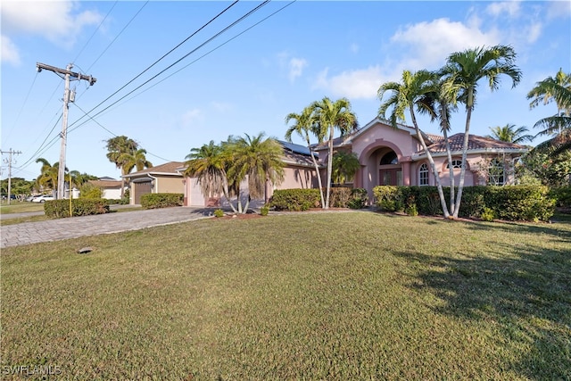 325 SE 21st St, Cape Coral, FL 33990 - view of front of house featuring stucco siding, solar panels, driveway, and a front yard