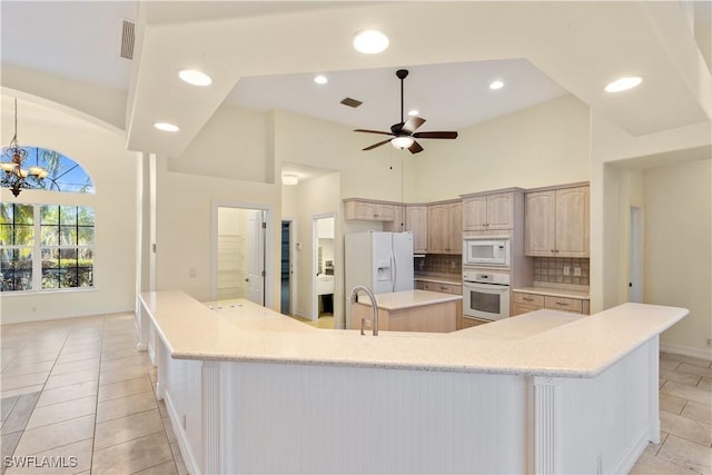 325 SE 21st St, Cape Coral, FL 33990 - kitchen featuring white appliances, a spacious island, a towering ceiling, a chandelier, and decorative backsplash