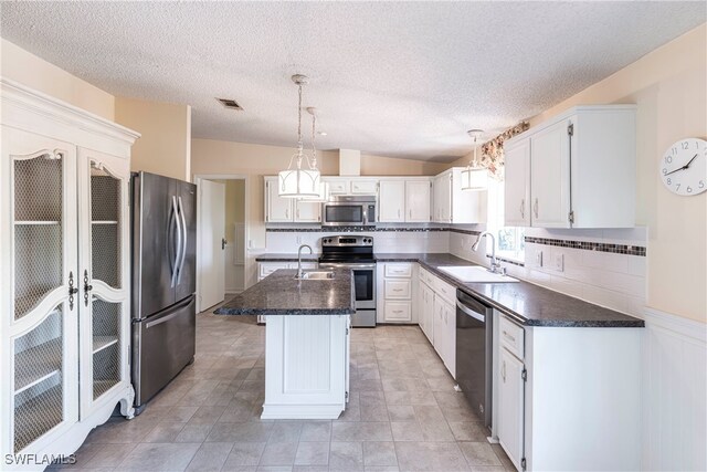 19703 Eagle Trace Ct, North Fort Myers, FL 33903 - kitchen with stainless steel appliances, dark countertops, tasteful backsplash, a kitchen island with sink, and a textured ceiling