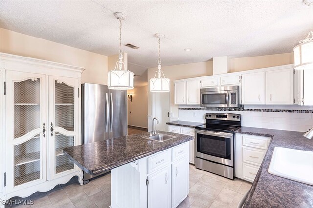 19703 Eagle Trace Ct, North Fort Myers, FL 33903 - kitchen with stainless steel appliances, white cabinets, pendant lighting, a kitchen island with sink, and a textured ceiling