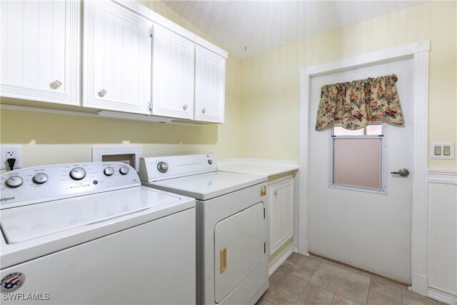 19703 Eagle Trace Ct, North Fort Myers, FL 33903 - laundry room with washer and clothes dryer, cabinet space, a textured ceiling, and light tile patterned flooring