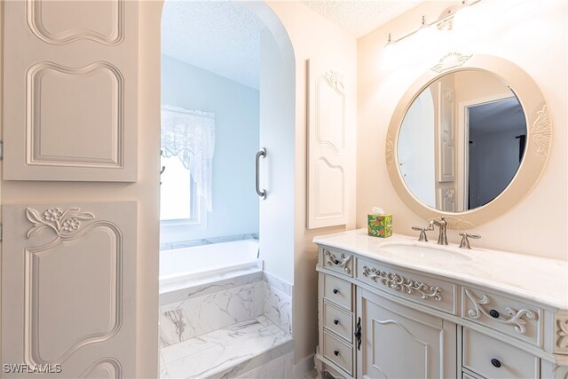 19703 Eagle Trace Ct, North Fort Myers, FL 33903 - bathroom with vanity, a tub with marble appearance, and a textured ceiling