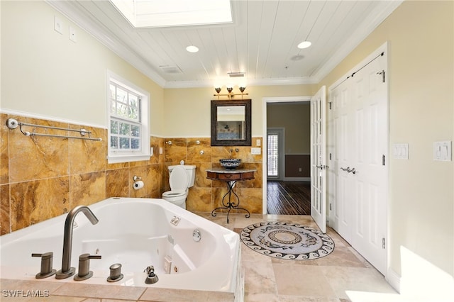 5697 Bay Point Rd, Bokeelia, FL 33922 - bathroom featuring toilet, crown molding, a whirlpool tub, tile walls, and a skylight