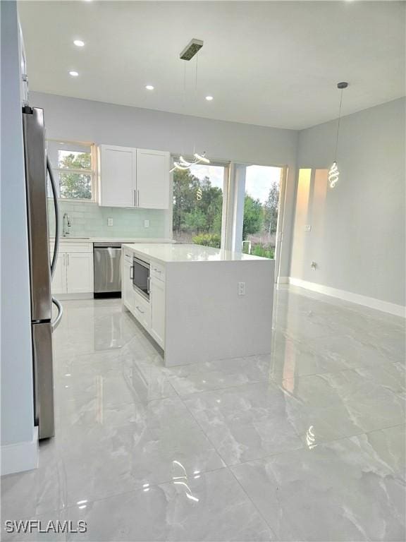 4391 66th Ave NE, Naples, FL 34120 - kitchen featuring stainless steel appliances, backsplash, white cabinets, light countertops, and light marble finish floors