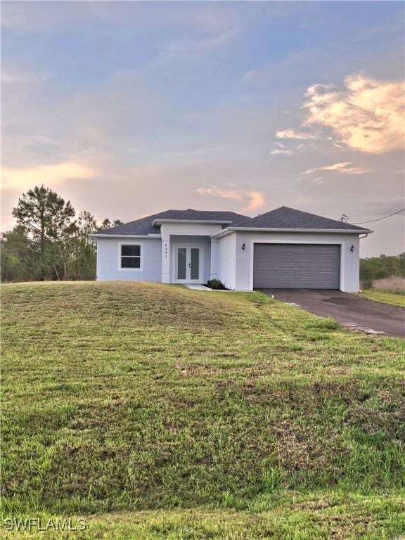 4391 66th Ave NE, Naples, FL 34120 - view of front of house featuring french doors, asphalt driveway, a garage, a front lawn, and stucco siding