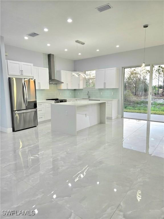 4391 66th Ave NE, Naples, FL 34120 - kitchen with freestanding refrigerator, wall chimney range hood, decorative backsplash, white cabinets, and recessed lighting