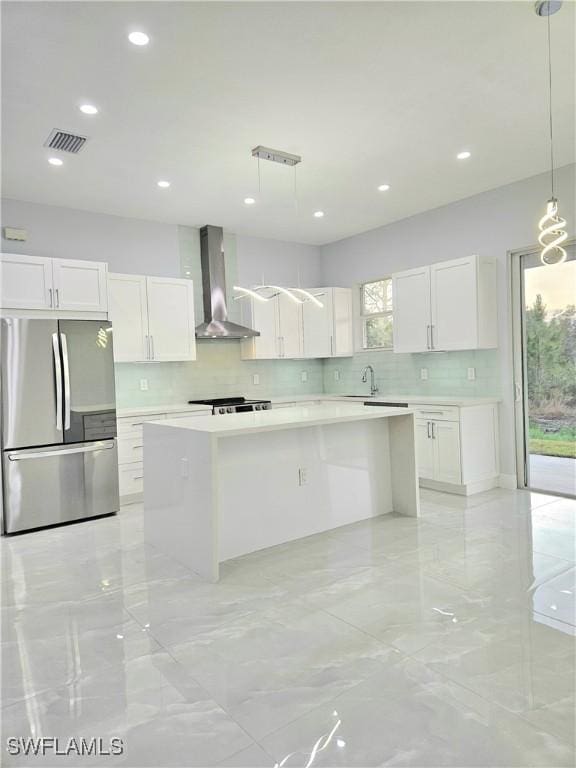 4391 66th Ave NE, Naples, FL 34120 - kitchen featuring freestanding refrigerator, wall chimney exhaust hood, a kitchen island, decorative backsplash, and recessed lighting