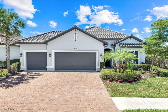 8396 Promoso Ct, Naples, FL 34114 - mediterranean / spanish house featuring an attached garage, decorative driveway, stucco siding, and a tiled roof