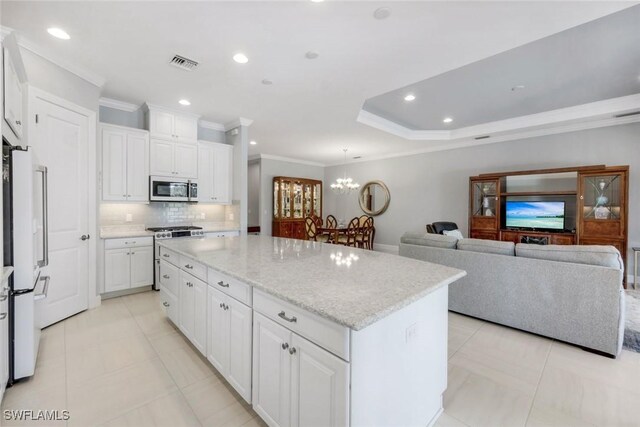 8396 Promoso Ct, Naples, FL 34114 - kitchen with appliances with stainless steel finishes, ornamental molding, a center island, decorative backsplash, and white cabinetry