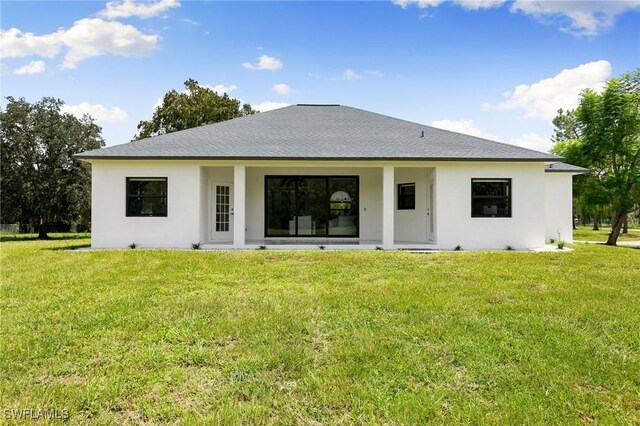 221 10th St SE, Naples, FL 34117 - rear view of property featuring stucco siding and a lawn
