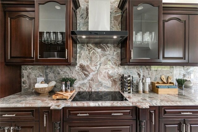 221 10th St SE, Naples, FL 34117 - kitchen featuring wall chimney exhaust hood, black electric stovetop, dark brown cabinets, decorative backsplash, and glass insert cabinets