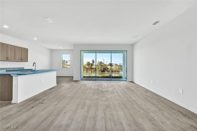 1414 NE 6th Ave, Cape Coral, FL 33909 - unfurnished living room featuring light wood finished floors, recessed lighting, baseboards, and a sink