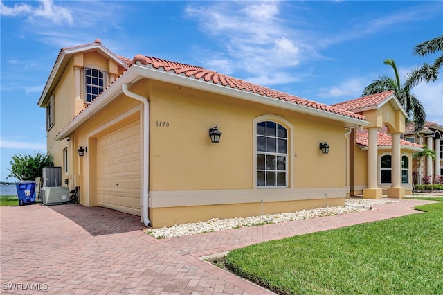 6140 River Shore Ct, North Fort Myers, FL 33917 - view of front of property featuring an attached garage, decorative driveway, a tile roof, stucco siding, and a front yard