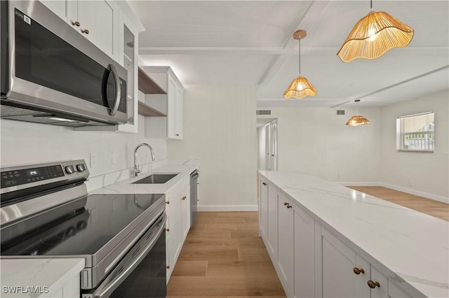 280 4th St S Unit 104, Naples, FL 34102 - kitchen with stainless steel appliances, a sink, light wood-type flooring, hanging light fixtures, and white cabinetry