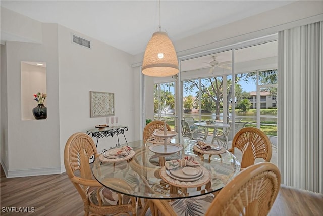 600 Diamond Cir Unit 607, Naples, FL 34110 - dining space featuring wood finished floors, a ceiling fan, a water view, and baseboards