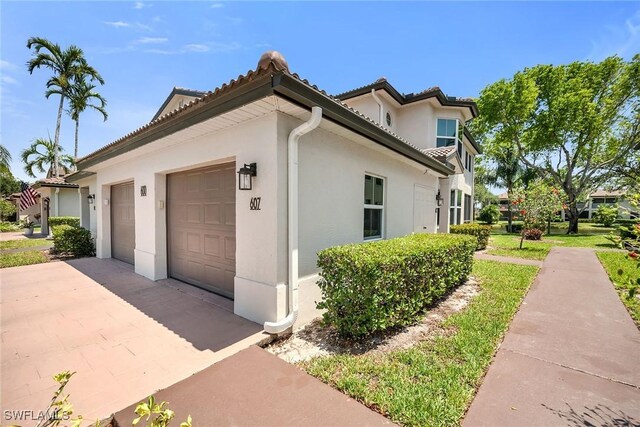 600 Diamond Cir Unit 607, Naples, FL 34110 - view of home's exterior featuring stucco siding, driveway, an attached garage, and a tile roof