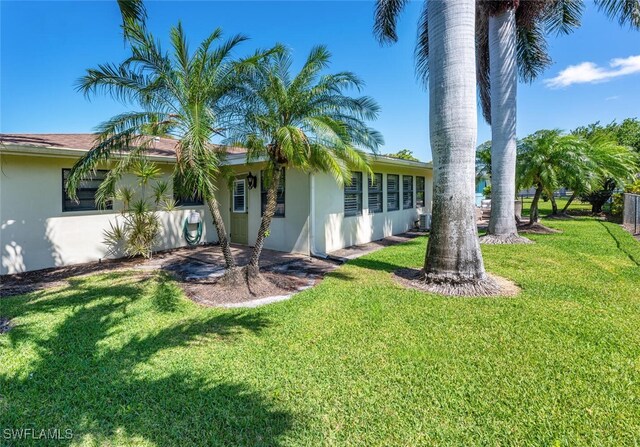 3586 Santiago Way, Naples, FL 34105 - view of property exterior with stucco siding, a yard, and central AC unit