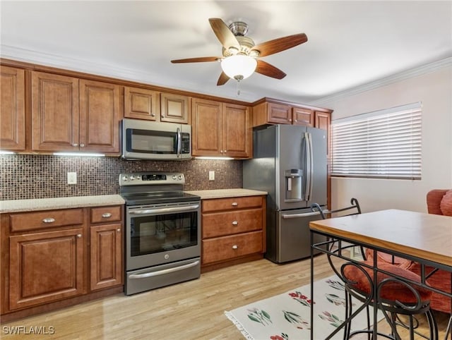 11921 Seabreeze Cove Ln Unit 104, Fort Myers, FL 33908 - kitchen with appliances with stainless steel finishes, brown cabinets, a ceiling fan, and ornamental molding