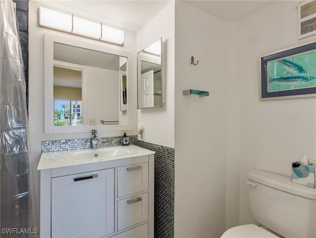 11921 Seabreeze Cove Ln Unit 104, Fort Myers, FL 33908 - bathroom featuring toilet, vanity, tile walls, a shower with shower curtain, and a wainscoted wall