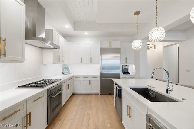 875 6th Ave S Unit 304, Naples, FL 34102 - kitchen with stainless steel appliances, a sink, wall chimney exhaust hood, light wood-style flooring, and light countertops