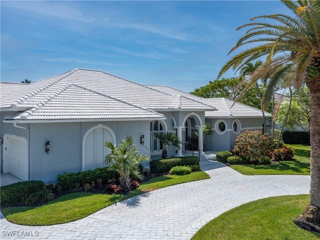 561 Conover Ct, Marco Island, FL 34145 - mediterranean / spanish house with stucco siding, a tile roof, a front lawn, and an attached garage