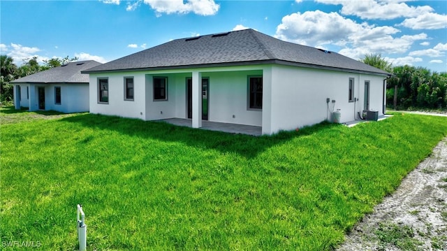 317 Lancelot Ave, Lehigh Acres, FL 33974 - back of house with a patio, a shingled roof, a yard, and stucco siding