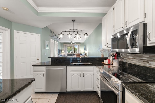 8161 Twelve Oaks Cir Unit 512, Naples, FL 34113 - kitchen with appliances with stainless steel finishes, a peninsula, decorative backsplash, white cabinetry, and crown molding