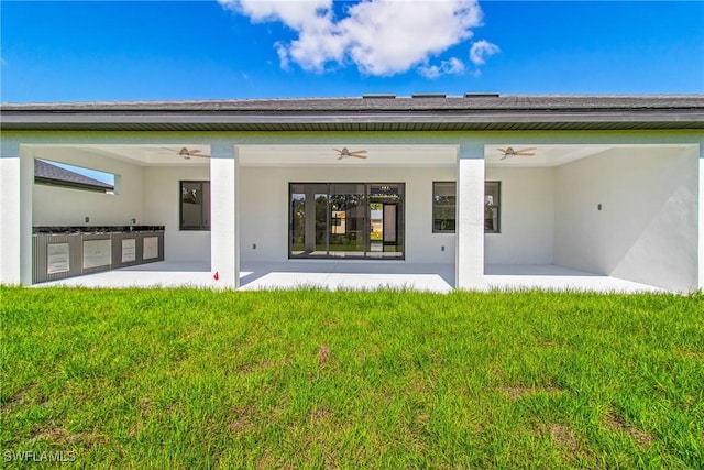 206 Jack Ave N, Lehigh Acres, FL 33971 - back of house with a ceiling fan, a patio area, a lawn, and stucco siding