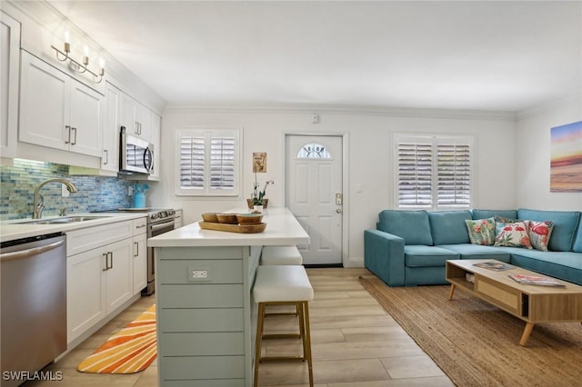 980 7th Ave S Unit 104, Naples, FL 34102 - kitchen with appliances with stainless steel finishes, white cabinets, a sink, light countertops, and a kitchen breakfast bar