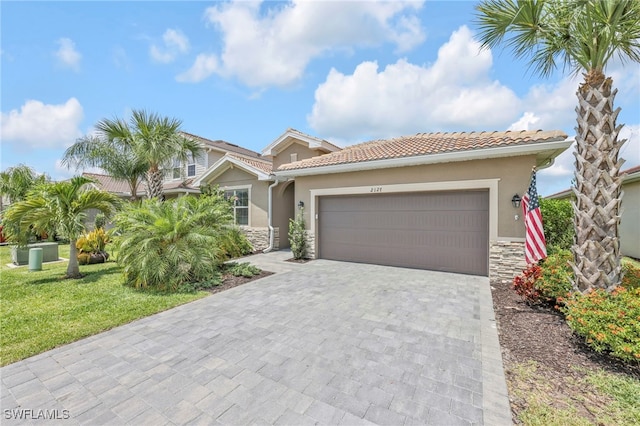 2127 Hamlin St, Naples, FL 34120 - view of front facade featuring stone siding, an attached garage, decorative driveway, and stucco siding