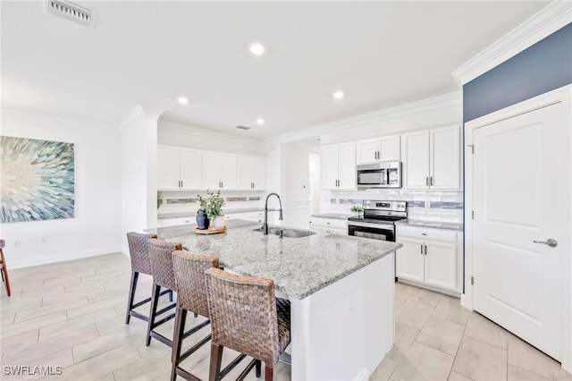2127 Hamlin St, Naples, FL 34120 - kitchen with a sink, stainless steel appliances, a kitchen bar, an island with sink, and white cabinets