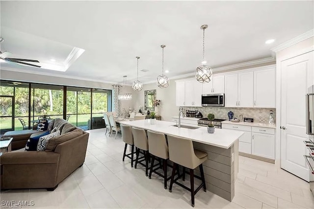 10367 Ventana Ln, Naples, FL 34120 - kitchen featuring appliances with stainless steel finishes, open floor plan, a sink, a breakfast bar, and light countertops