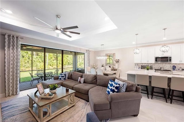 10367 Ventana Ln, Naples, FL 34120 - living room featuring a ceiling fan, healthy amount of natural light, a raised ceiling, ornamental molding, and baseboards