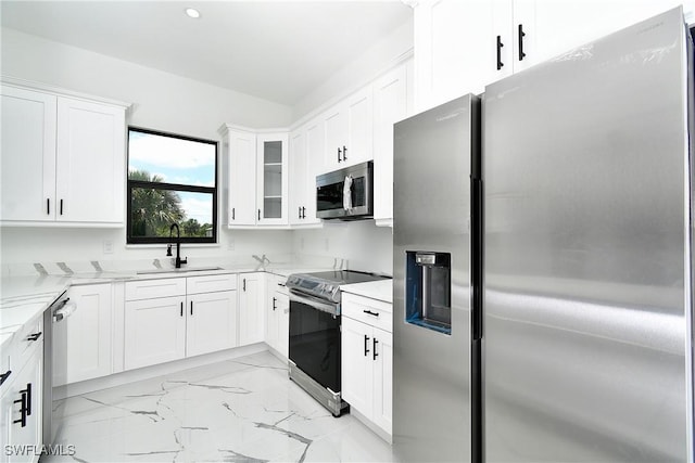 3808 2nd St W, Lehigh Acres, FL 33971 - kitchen featuring appliances with stainless steel finishes, a sink, light marble finish floors, light stone countertops, and white cabinetry