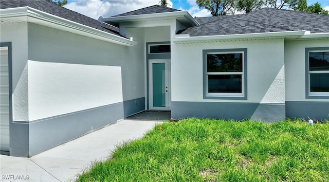 3808 2nd St W, Lehigh Acres, FL 33971 - view of exterior entry featuring roof with shingles and stucco siding