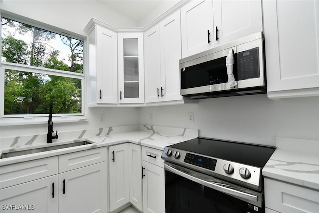 3808 2nd St W, Lehigh Acres, FL 33971 - kitchen with stainless steel appliances, a sink, white cabinets, and glass insert cabinets