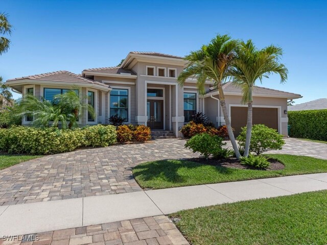 811 Manor Ter, Marco Island, FL 34145 - prairie-style home featuring an attached garage, stucco siding, decorative driveway, and a tile roof