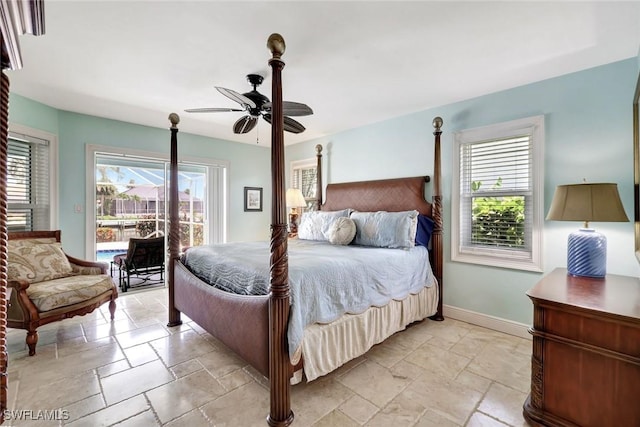 bedroom featuring stone tile floors, access to exterior, multiple windows, and baseboards