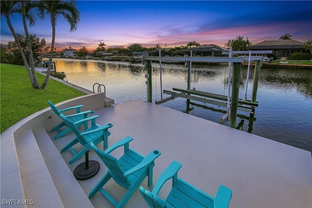 dock featuring boat lift, a water view, and a yard