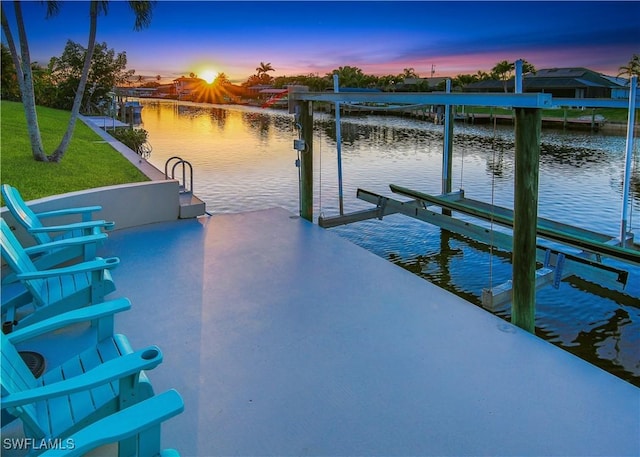 dock with a water view, a lawn, and boat lift