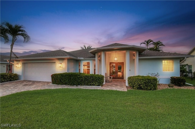 view of front facade featuring stucco siding, french doors, a garage, and a lawn