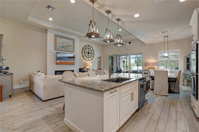 9292 Cayman Dr, Naples, FL 34114 - kitchen featuring a fireplace, a sink, light wood-style floors, open floor plan, and light stone countertops